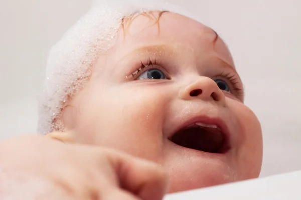 Enfant de 1 an riant dans un bain avec mousse sur la tête — Photo