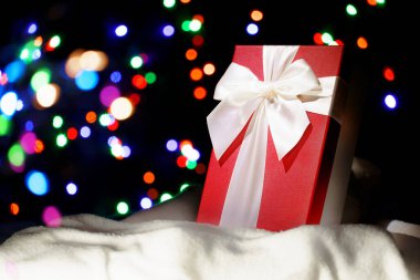 Fosforlu ışıkların arka planında karda bir hediye. Yılbaşı geçmişi. Kartpostal, afiş