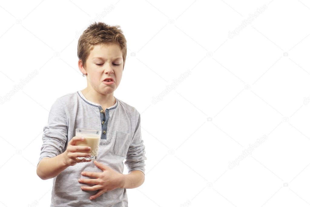 disgruntled child with a glass of milk isolated on white background. the boy looks with disgust at the milk