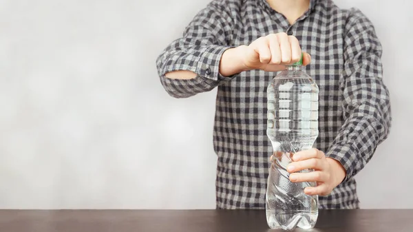 Boy opens a plastic bottle of water, free space — Stockfoto