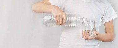 Çocuk bardağa su dolduruyor. kopyalama alanı olan gri arkaplan.