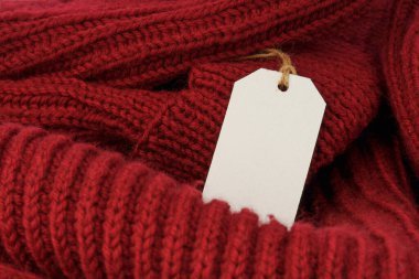 Kırmızı örülmüş yün kumaş dokusu arka planında boş fiyat etiketi var. Alışveriş düzeni