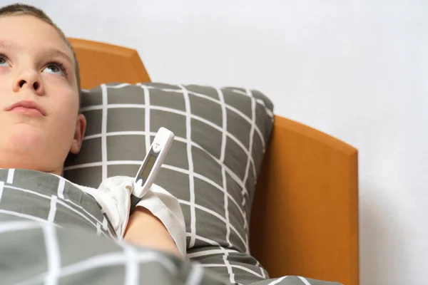 Trauriger kranker Junge mit Thermometer im Bett liegend — Stockfoto