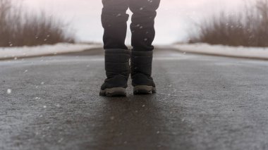 childrens feet in warm shoes on the road. back view