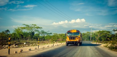 Yellow bus on the Rural road in Dominican Republic clipart