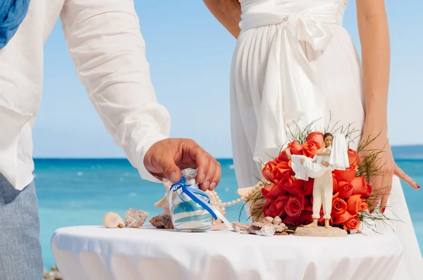 Hands of bride holding vase with colorful sand during wedding party