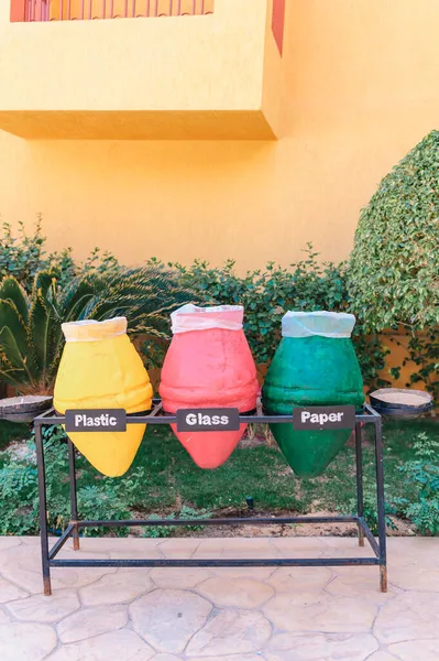 Tiga tempat sampah untuk daur ulang. Mengurutkan serpihan-serpihan plastik, kaca dan kertas. Foto close-up dari pot berwarna-warni yang digunakan sebagai wadah sampah. Hal ini sangat penting bagi planet kita dan ekologi untuk mengurutkan limbah Anda — Stok Foto