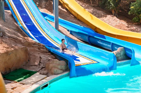 Sakta ner och kör en sväng i AQUA PARK, HOLIDAY FUN. Ett barn som åker vattenrutschbana — Stockfoto