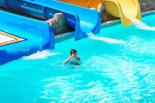 BOY SLIDING DOWN A SLIDE IN AQUA PARK, HOLIDAY FUN. A child riding a water slide — Stock Photo, Image