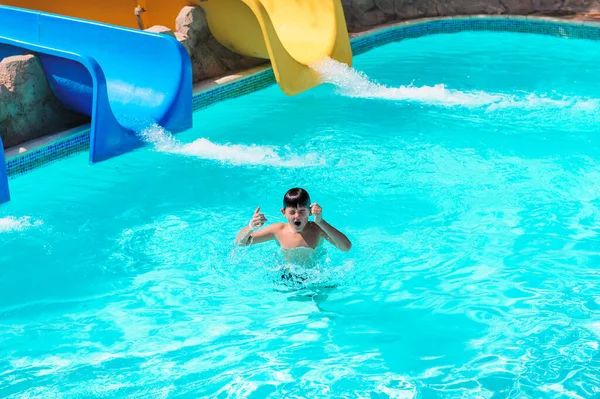 BOY SLIDING DOWN A SLIDE IN AQUA PARK, HOLIDAY FUN. A child riding a water slide — Stock Photo, Image