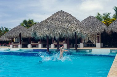 Mutlu çekici adam mavi yüzme havuzunda yüzüyor. Açık hava tatil köyü, lüks otel. Deniz kenarında yaz kaplıcası. Tropik cennet. Dominik Cumhuriyeti, Seyşeller, Karayipler, Bahamalar.