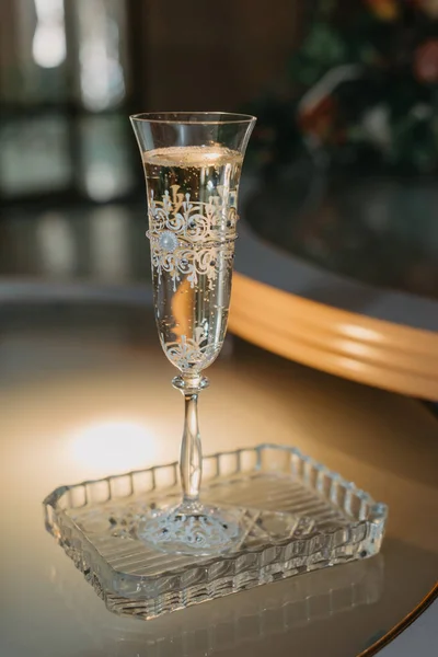 Şampanyalı bir düğün kadehi, kristal bir tabakta masanın üzerinde duruyor. — Stok fotoğraf