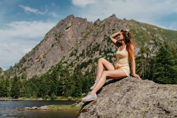 Turist kız gölün, kozalaklı ormanın ve dağlardaki turkuaz gölün kıyısındaki büyük taşın üzerindeki sihirli manzaranın tadını çıkarıyor. Doğal Park 'ta yürüyüş. Tatlı kız.