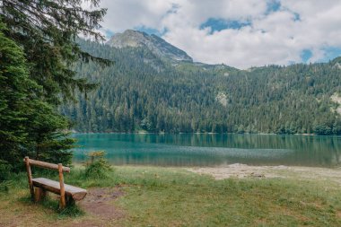 Rahat ol. Göl kenarında dinlen. Göle ve dağlara bakan ahşap bir bank. Güzel mistik göl. Kara Göl, Durmitor Ulusal Parkı. Karadağ