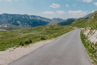 Bulutlu gökyüzü ve güneş ışığı olan boş asfalt yol. Avrupa Alplerindeki ülke yolu.