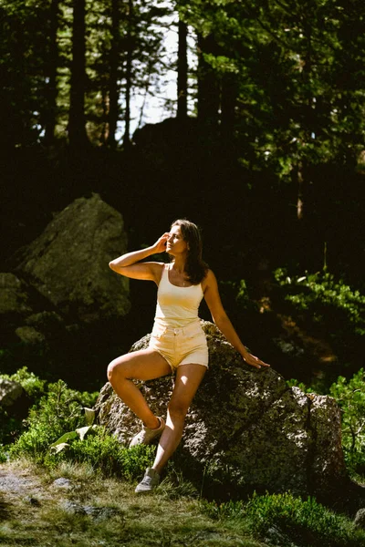 穿着黄色T恤和黄色短裤的年轻漂亮的姑娘坐在美丽的峡谷上方的石头上。在山上旅行的人。嬉皮士女孩在山上。穿着格子衬衫的时髦女人 — 图库照片