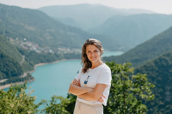 Meisjestoerist staat aan de oever van een meer in de bergen. prachtig landschap, Piva Lake in Montenegro.. Vrouw staat aan de kust van Piva meer bij zonsondergang in de zomer. Landschap met meisje, beroemd — Stockfoto