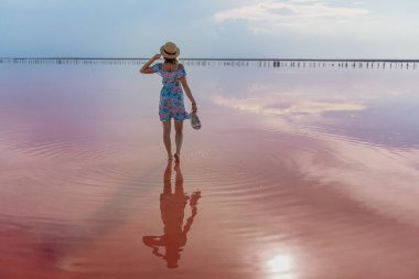 Gün batımında ünlü pembe tuz gölünde poz veren kız. Göldeki yansıma