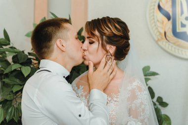 Düğün: birbirine aşık genç bir çift gelin ve damat bir buket çiçek tutarak birbirlerine sarılıyorlar. Düğün töreninde iki aşık kalbi. Gülümseyen mutlu yeni evliler. Gelin ve damat bakın.