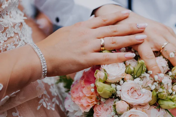 HONEYMOONS HANDS EM UM BOUQUET QUERDO DE FLORES. Mãos e anéis no buquê de casamento — Fotografia de Stock