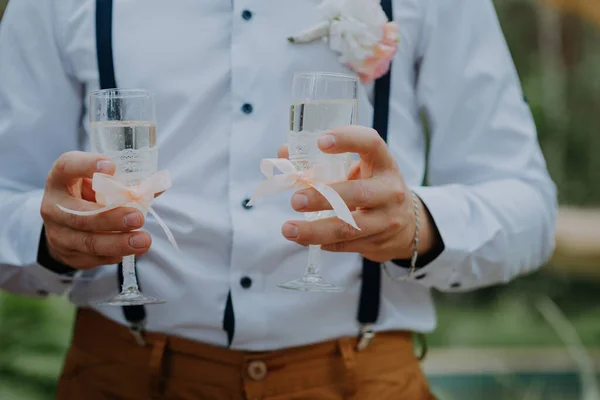 Snygg brudgum med två glas champagne. Snygg glad man i elegant kostym som håller två glas champagne och firar sin bröllopsdag — Stockfoto