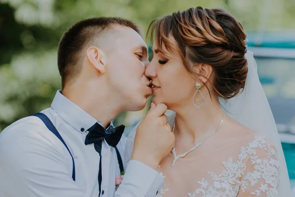 Juste marié couple de mariage est debout près de la voiture vintage rétro dans le parc. Journée ensoleillée d'été en forêt. mariée dans une élégante robe blanche avec bouquet et marié élégant dans l'amour câlin. Mariée et marié — Photo