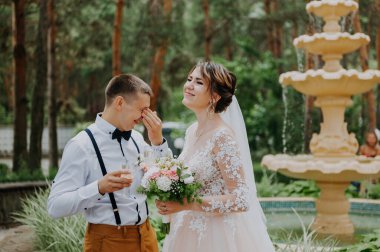 Gelin ve damat parkta şampanya kadehleriyle düğün günlerini kutluyorlar. Sevgili bir çift yeni evli şampanya içer, sarılır ve fıskiyenin arka planında öpüşür. Kapat.