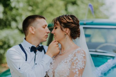 Yeni evli bir çift parktaki antika arabanın yanında duruyor. Ormanda güneşli bir yaz günü. Şık, beyaz elbiseli, buketli gelin ve aşık damat. Gelin ve damat