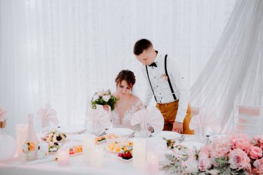 Düğün ziyafetinde romantik öpüşme gelin ve damat. Düğün ziyafeti. Gelin ve damat masada. Herkes eğleniyor. Gülümse ve öp. Düğün ziyafeti. gelin ve damat bir restoranda.