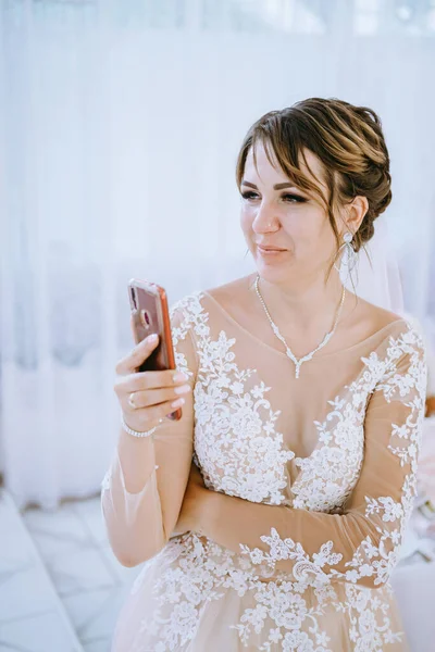 Pengantin wanita muda yang bersemangat dalam gaun pengantin putih melakukan foto selfie di ponsel menunjuk ibu jari pada dirinya sendiri terisolasi pada potret studio latar pirus biru. Konsep pesta perayaan upacara — Stok Foto