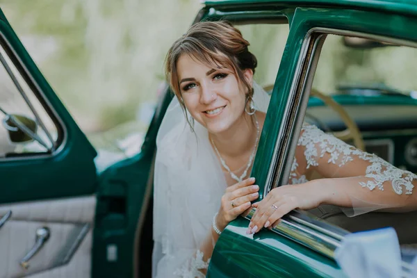 Boda novia descanso y divertirse en verde vintage coche retro después de la boda. Concepto de luna de miel. Mujer del coche feliz en viejo coche retro vintage. Mujer joven conduciendo en viaje por carretera en hermoso día soleado de verano. —  Fotos de Stock