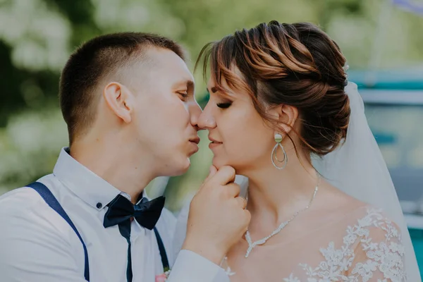 La pareja de recién casados está de pie cerca del coche retro vintage en el parque. Día soleado de verano en el bosque. novia en vestido blanco elegante con ramo y novio elegante en el amor abrazo. Novia y novio —  Fotos de Stock