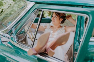 Gelinin dinlenmesi ve düğünden sonra eski model yeşil arabada iyi eğlenceler. Balayı konsepti. Eski model bir arabada mutlu bir araba kadını. Güzel güneşli bir yaz gününde araba süren genç bir kadın..