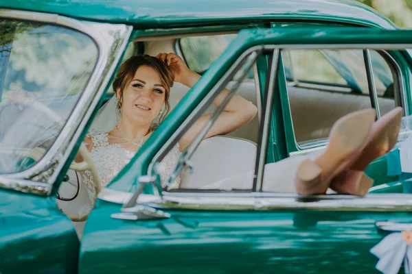 Gelinin dinlenmesi ve düğünden sonra eski model yeşil arabada iyi eğlenceler. Balayı konsepti. Eski model bir arabada mutlu bir araba kadını. Güzel güneşli bir yaz gününde araba süren genç bir kadın.. — Stok fotoğraf