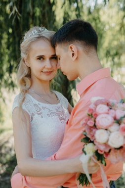 Gelin ve damat gün açık havada yürüyüş düğününde doğa bahar. Gelin Çift, mutlu yeni evli kadın ve yeşil park kucaklayan adam. Sevgi dolu evlilik çift açık. Gelin ve damat, düğün çekim