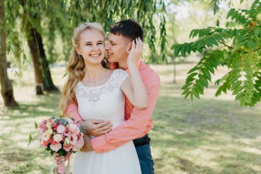 Gelin ve damat gün açık havada yürüyüş düğününde doğa bahar. Gelin Çift, mutlu yeni evli kadın ve yeşil park kucaklayan adam. Sevgi dolu evlilik çift açık. Gelin ve damat, düğün çekim