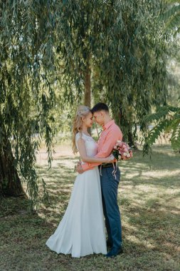 Gelin ve damat gün açık havada yürüyüş düğününde doğa bahar. Gelin Çift, mutlu yeni evli kadın ve yeşil park kucaklayan adam. Sevgi dolu evlilik çift açık. Gelin ve damat, düğün çekim