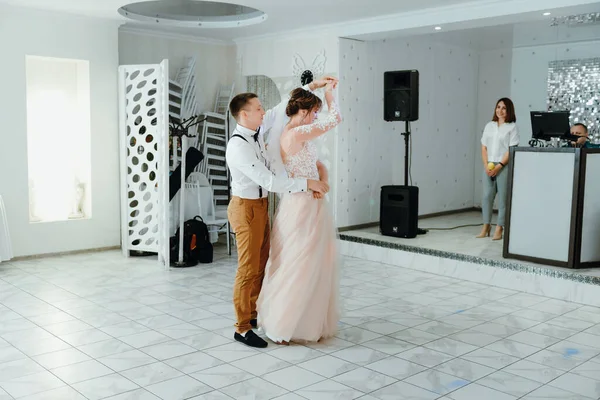 beautiful caucasian couple just married and dancing their first dance. Just married couple dancing in front of their unrecognizable friends.
