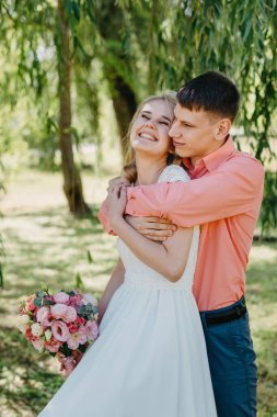 Gelin ve damat gün açık havada yürüyüş düğününde doğa bahar. Gelin Çift, mutlu yeni evli kadın ve yeşil park kucaklayan adam. Sevgi dolu evlilik çift açık. Gelin ve damat, düğün çekim