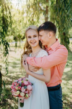 Gelin ve damat gün açık havada yürüyüş düğününde doğa bahar. Gelin Çift, mutlu yeni evli kadın ve yeşil park kucaklayan adam. Sevgi dolu evlilik çift açık. Gelin ve damat, düğün çekim