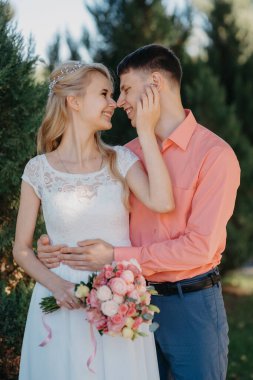 Gelin ve damat gün açık havada yürüyüş düğününde doğa bahar. Gelin Çift, mutlu yeni evli kadın ve yeşil park kucaklayan adam. Sevgi dolu evlilik çift açık. Gelin ve damat, düğün çekim