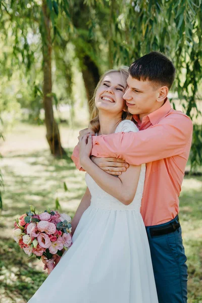 Gelin ve damat gün açık havada yürüyüş düğününde doğa bahar. Gelin Çift, mutlu yeni evli kadın ve yeşil park kucaklayan adam. Sevgi dolu evlilik çift açık. Gelin ve damat, düğün çekim