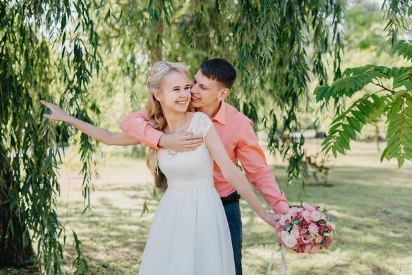 Gelin ve damat gün açık havada yürüyüş düğününde doğa bahar. Gelin Çift, mutlu yeni evli kadın ve yeşil park kucaklayan adam. Sevgi dolu evlilik çift açık. Gelin ve damat, düğün çekim