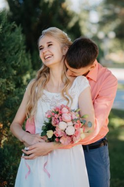 Gelin ve damat gün açık havada yürüyüş düğününde doğa bahar. Gelin Çift, mutlu yeni evli kadın ve yeşil park kucaklayan adam. Sevgi dolu evlilik çift açık. Gelin ve damat, düğün çekim