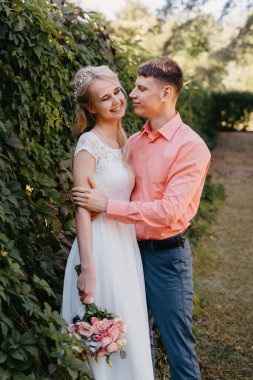 Gelin ve damat gün açık havada yürüyüş düğününde doğa bahar. Gelin Çift, mutlu yeni evli kadın ve yeşil park kucaklayan adam. Sevgi dolu evlilik çift açık. Gelin ve damat, düğün çekim