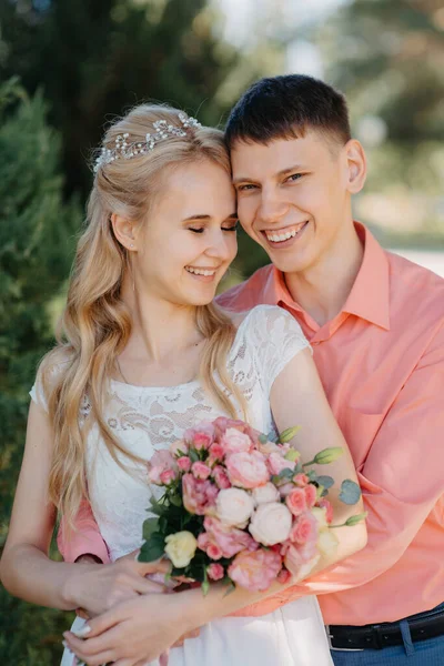 Gelin ve damat gün açık havada yürüyüş düğününde doğa bahar. Gelin Çift, mutlu yeni evli kadın ve yeşil park kucaklayan adam. Sevgi dolu evlilik çift açık. Gelin ve damat, düğün çekim