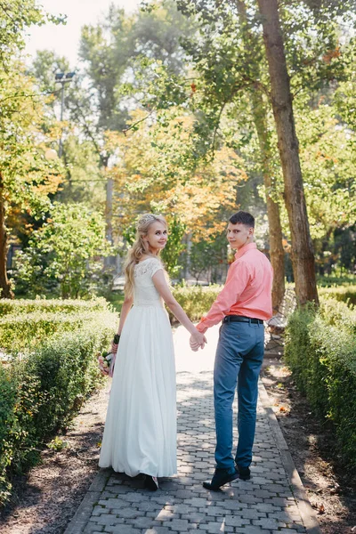 Noiva e noivo no dia do casamento andando ao ar livre na natureza de primavera. Casal nupcial, mulher recém-casada feliz e homem abraçando no parque verde. Casal de amor ao ar livre. Tiro de casamento de noiva e noivo em — Fotografia de Stock