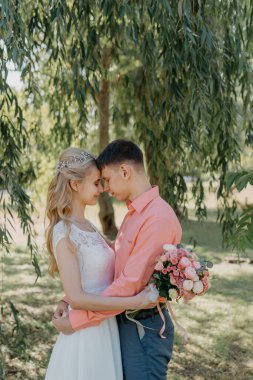 Gelin ve damat gün açık havada yürüyüş düğününde doğa bahar. Gelin Çift, mutlu yeni evli kadın ve yeşil park kucaklayan adam. Sevgi dolu evlilik çift açık. Gelin ve damat, düğün çekim