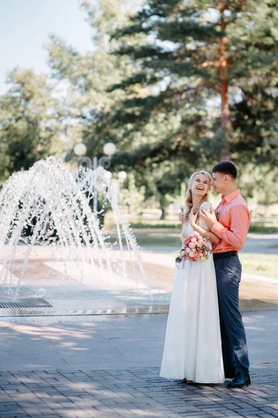 Happy bride and groom on wedding walk near fountain. Bride and groom having a romantic moment on their wedding day. — 图库照片