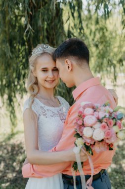 Gelin ve damat gün açık havada yürüyüş düğününde doğa bahar. Gelin Çift, mutlu yeni evli kadın ve yeşil park kucaklayan adam. Sevgi dolu evlilik çift açık. Gelin ve damat, düğün çekim